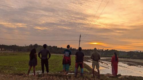 a group of people standing in a field watching the sunset at Crossroads Hostel 1957 in Wayanad