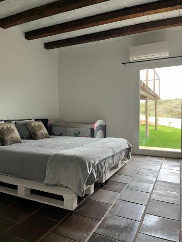 um quarto com uma cama e uma grande janela em Nature&Soul - Sol em Vila do Bispo