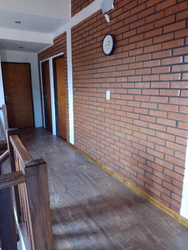 an empty room with a brick wall and a clock at Hospedaje Los Laureles in Wanda