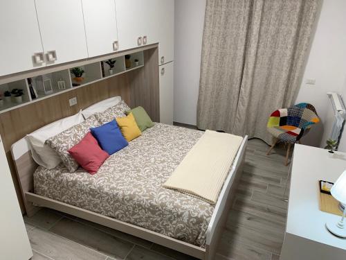 Dormitorio pequeño con cama con almohadas coloridas en Casa da Lory, en Foggia