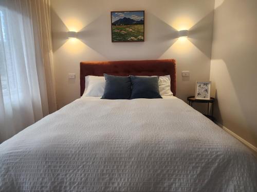 a bedroom with a large white bed with two lights at 5 By the Church in Port Fairy