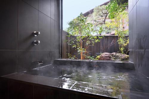 a bathroom with a bath tub with a pond at Oni no Sumika in Izu