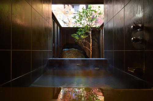 a bathroom with a tub with a reflection of a tree at Oni no Sumika in Izu