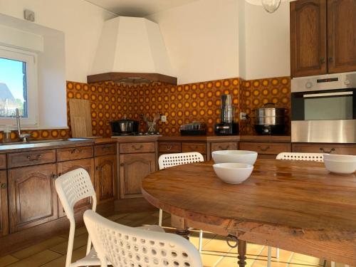 a kitchen with a wooden table and white chairs at Gîte ti Goudoul éco responsable BB friendly in Moëlan-sur-Mer