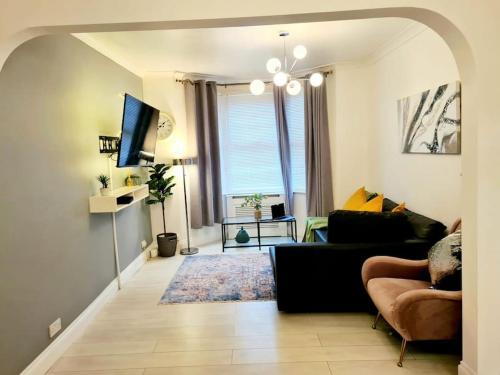 ein Wohnzimmer mit einem Sofa und einem TV in der Unterkunft Private House With FREE Parking in London