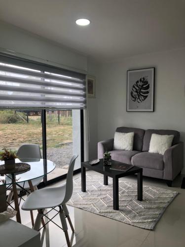 a living room with a couch and a table and chairs at Departamento Los Canelos, a metros de Avenida Las Industrias- Incluye, NETFLIX DirecTV aire acondicionado, Internet in Los Ángeles