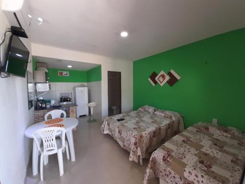 um quarto com paredes verdes e duas camas e uma mesa em Pousada Chalés do Castelo em Icapuí
