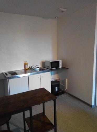 une cuisine avec une table et un four micro-ondes sur un comptoir dans l'établissement Appartement tout équipé hypercentre Limoges, à Limoges
