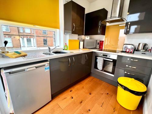 a kitchen with stainless steel appliances and a wooden floor at Driftwood Studio in Cromer