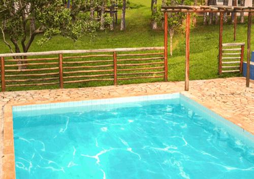 a large blue swimming pool in front of a fence at Pousada Doce Recanto in Soledade de Minas