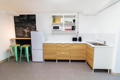 a kitchen with a white refrigerator and two stools at Koala Hostel in Alicante