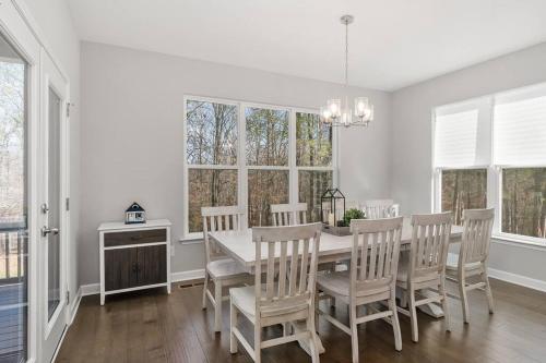 a dining room with a table and chairs and windows at Beautiful Home with Lake and Marina Access, Firepit, Golf Cart Included in Estill Springs