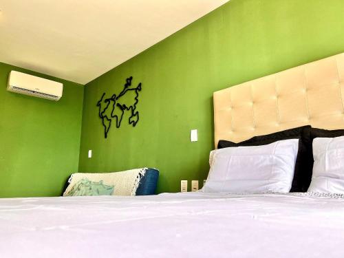 een slaapkamer met een groene muur en een bed bij Ilusion: perto de tudo em Ponta Negra - AlfaTemporada in Natal