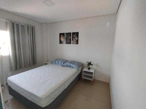 ein Schlafzimmer mit einem Bett in einem weißen Zimmer in der Unterkunft Happy Apartamentos Unidade 2 in Cascavel