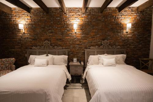 two beds in a room with a brick wall at Villa Toscana ValQuirico Lofts & Suites Hotel Boutique in Santeagueda