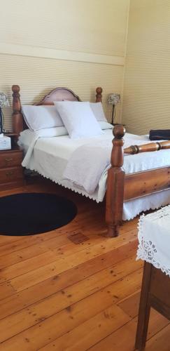 Gum Paddock Country Cottage في بروكن هيل: سرير مع اطار خشبي في الغرفة