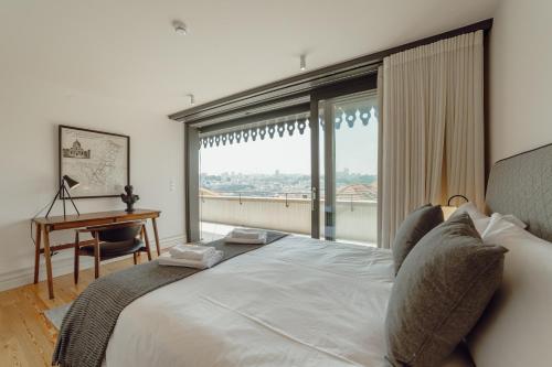 Schlafzimmer mit einem großen Bett, einem Schreibtisch und einem Fenster in der Unterkunft Downtown Penthouse With River View by Vacationy in Porto