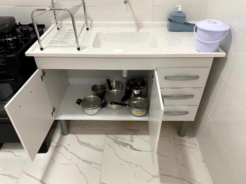 um lavatório de cozinha com panelas e frigideiras numa prateleira em Studio na praia da ENSEADA no Guarujá