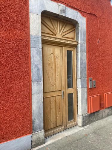 a wooden door on the side of a red building at Ginkobiloba : Appartement cosy en cœur de ville in Bagnères-de-Bigorre
