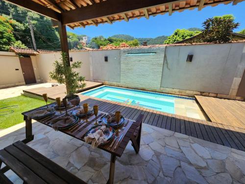 un patio con una mesa y una piscina en CASA ALECRIM PISCINA PRIVATIVA COM Dec MOVEL Ideal Crianças en Niterói