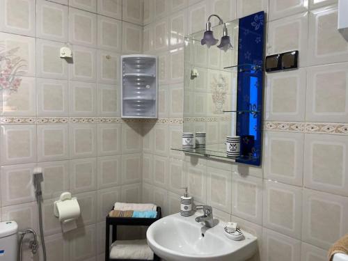 a white bathroom with a sink and a mirror at Villa Charaf in Agadir