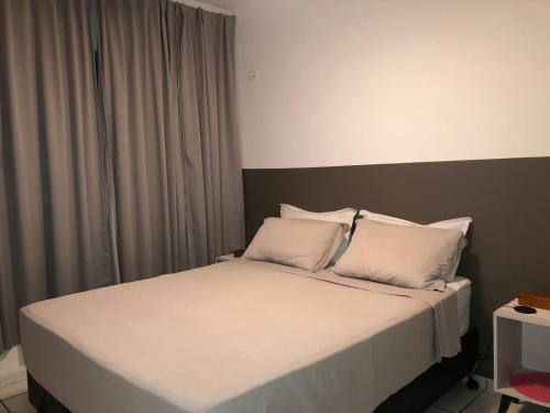 een slaapkamer met een bed met witte lakens en kussens bij Talats_HomeCharm in São Luís