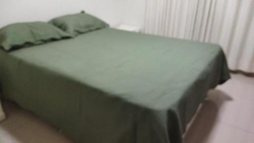 a green bed with a green blanket on it at CALDAS NOVAS - GO Apartamento Parque das Aguas Quentes bloco 3 - em frente Clube Privê in Caldas Novas