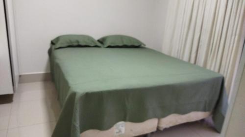 - un petit lit avec un couvre-lit vert dans l'établissement CALDAS NOVAS - GO Apartamento Parque das Aguas Quentes bloco 3 - em frente Clube Privê, à Caldas Novas