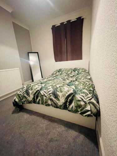 ein Schlafzimmer mit einem Bett mit einer grünen Decke in der Unterkunft Shou’s guest house in Newport