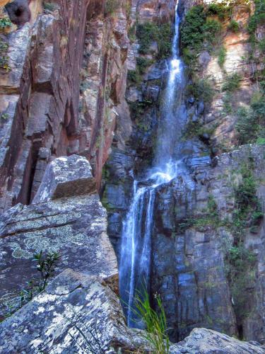 a waterfall on the side of a rocky cliff at Pousada Mandalla in Serra do Cipo