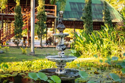 a fountain in a pond in a garden at Portales del Tayrona Garden Hotel in Calabazo