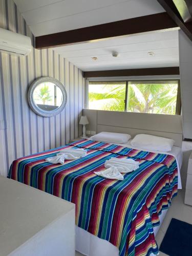 1 dormitorio con 1 cama con toallas en Flat Beach Class Resort Muro Alto, en Porto de Galinhas