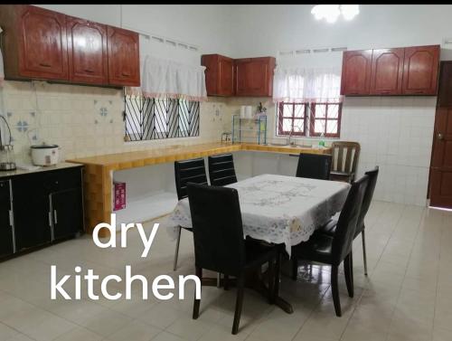 a kitchen with a table and chairs and a kitchen with a kitchen at D'Aman Guesthouse Pontian in Kampong Parit Tengah