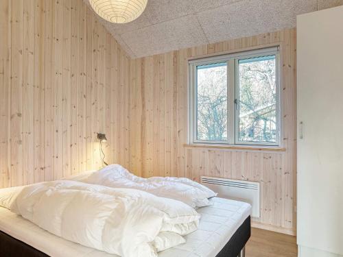 a bedroom with a bed with white sheets and a window at 8 person holiday home in Dannemare-By Traum in Dannemare