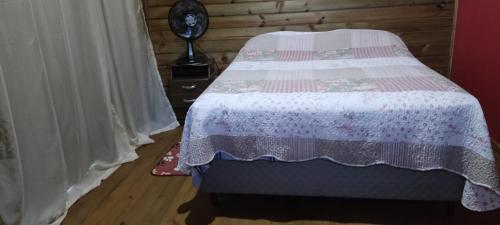 1 dormitorio con 1 cama con edredón rosa y blanco en Chalé do Alemão, en Imbituba
