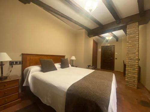 a bedroom with a large bed and a brick wall at Hotel Rural El Lagar de Nemesio in Perales de Tajuña