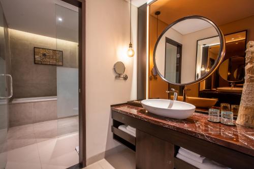 a bathroom with a sink and a mirror and a shower at Sanctoo Suites & Villas in Gianyar