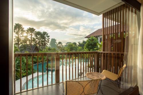 a balcony with a table and chairs and a view of a pool at Sanctoo Suites & Villas in Sukawati