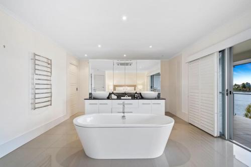 a white bathroom with a tub and a kitchen at Sorrento Waterfront Retreat,Pool in Gold Coast