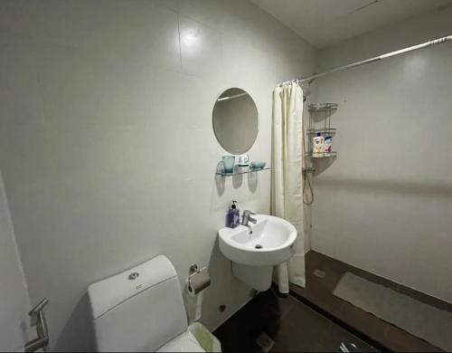 y baño con aseo, lavabo y espejo. en Sky Staycation KL Greenbelt, Isabel's Makati Rooms en Manila