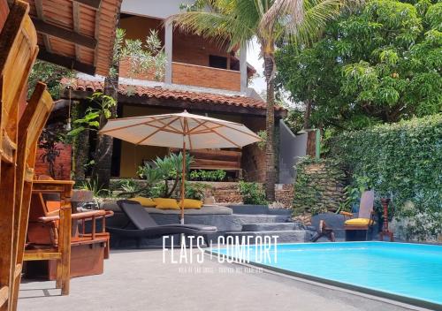 a patio with an umbrella and a swimming pool at NOVIDADE FLATS COMFORT na Vila de São Jorge - Chapada dos Veadeiros in Sao Jorge