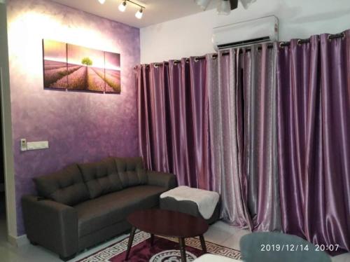 - un salon avec des rideaux violets et un canapé dans l'établissement Lavender home, à Nilai