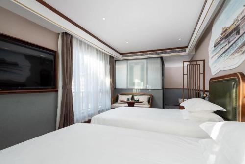 a hotel room with two beds and a flat screen tv at Nostalgia S Hotel - Beijing Xidan Financial Street in Beijing