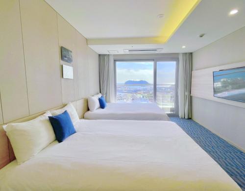 a hotel room with two beds and a large window at Hotel bridge Seogwipo in Seogwipo