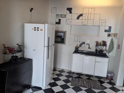 uma cozinha com um frigorífico branco e um piso em xadrez em Youkoso Hostel em Florianópolis