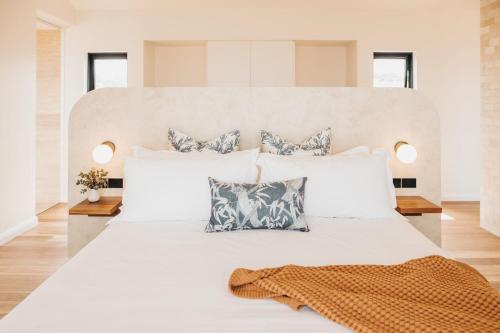 a white bedroom with a large white bed with pillows at StowAway Kangaroo Island in Stokes Bay