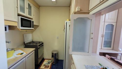 a small kitchen with a stove and a refrigerator at Apto ao lado da rua coberta in Gramado