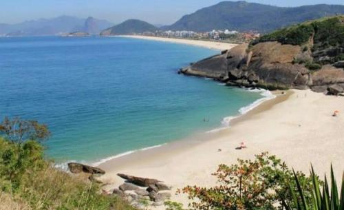 einen Strand mit Menschen auf Sand und Wasser in der Unterkunft Camboinhas LOFT Temporada in Niterói