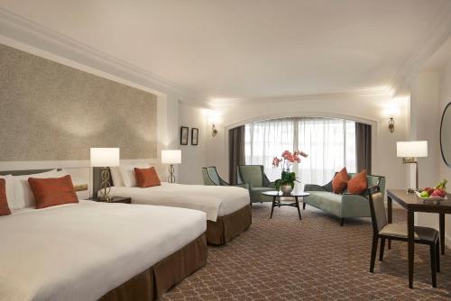 シンガポールにあるOrchard Rendezvous Hotel by Far East Hospitalityのベッド2台、テーブルと椅子が備わるホテルルームです。