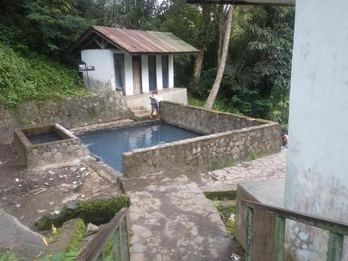 a swimming pool with a stone wall and a building at Mushtinal Guest House in Ende